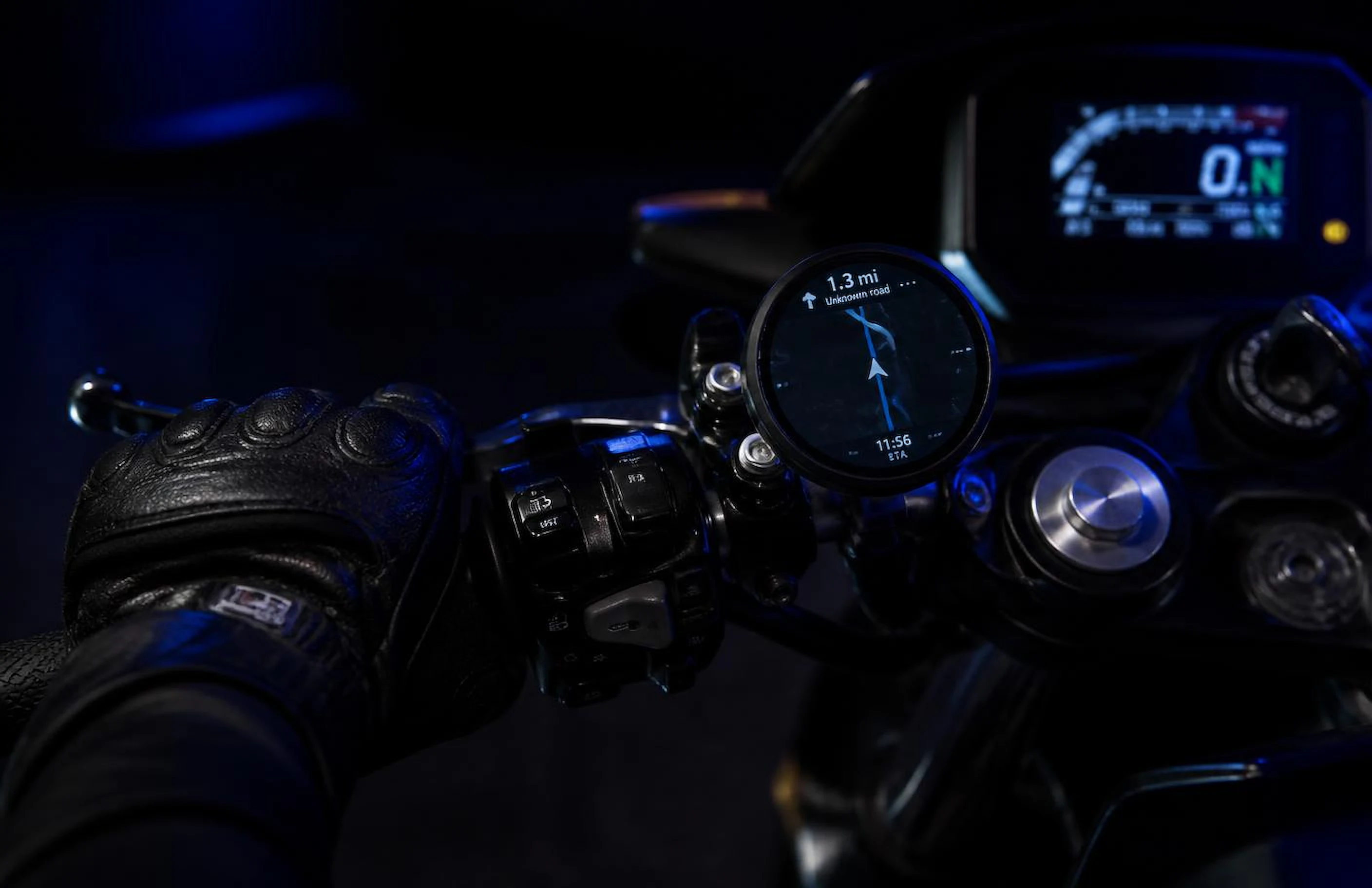 Gloved hand on a motorcycle grip beside a mounted RYDARO navigator